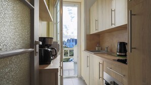 A narrow kitchen with wooden cabinets, a coffee maker, and a view of the outside. - Studio "Direct Sea View for 2 People" with Sea View, 2 Balconies and Wi-Fi (Saint-Quay Portrieux)