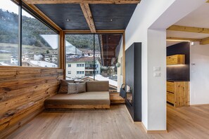 A modern interior with a wooden bench, large windows, and a kitchen area.