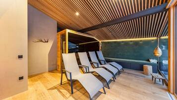 Un interior moderno con techo de listones de madera, un área de estar con sillones acolchados, un banco e iluminación colgante.