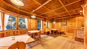 A wooden interior with multiple tables and chairs, large windows, and a ceiling with exposed beams. - Apartment 'Naturoase Stegerhof Iris' with Mountain View, Shared Pool and Sauna (Truden im Naturpark)