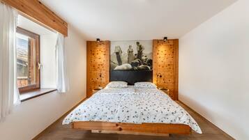 Une chambre avec un lit en bois, une fenêtre avec des rideaux, un tableau au mur et un plafond en bois.