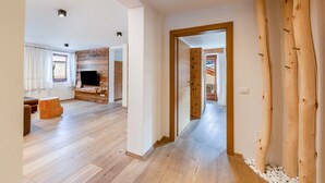 A spacious living area with a wooden floor, a television, and a fireplace. - Apartment 'Naturoase Stegerhof Iris' with Mountain View, Shared Pool and Sauna (Truden im Naturpark)