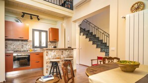 A modern kitchen with wooden cabinets, a dining area with a table and chairs, and a staircase.