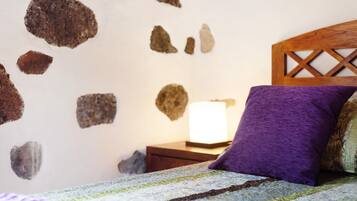 A bedroom with a bed, a nightstand, a lamp, and a wall with stone decorations.