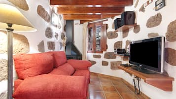 A cozy room with a red sofa, a television, and stone walls.