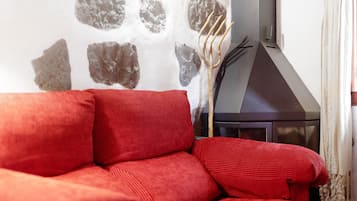 A red sofa in a room with a stone wall and a fireplace.