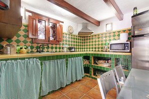 Une cuisine avec un crédence à carreaux verts et blancs, des armoires en bois, un réfrigérateur en acier inoxydable et un four à micro-ondes.