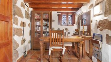 Ein rustikales Interieur mit einem Holztisch, Stühlen, einem Bücherregal und einer Steinwand.