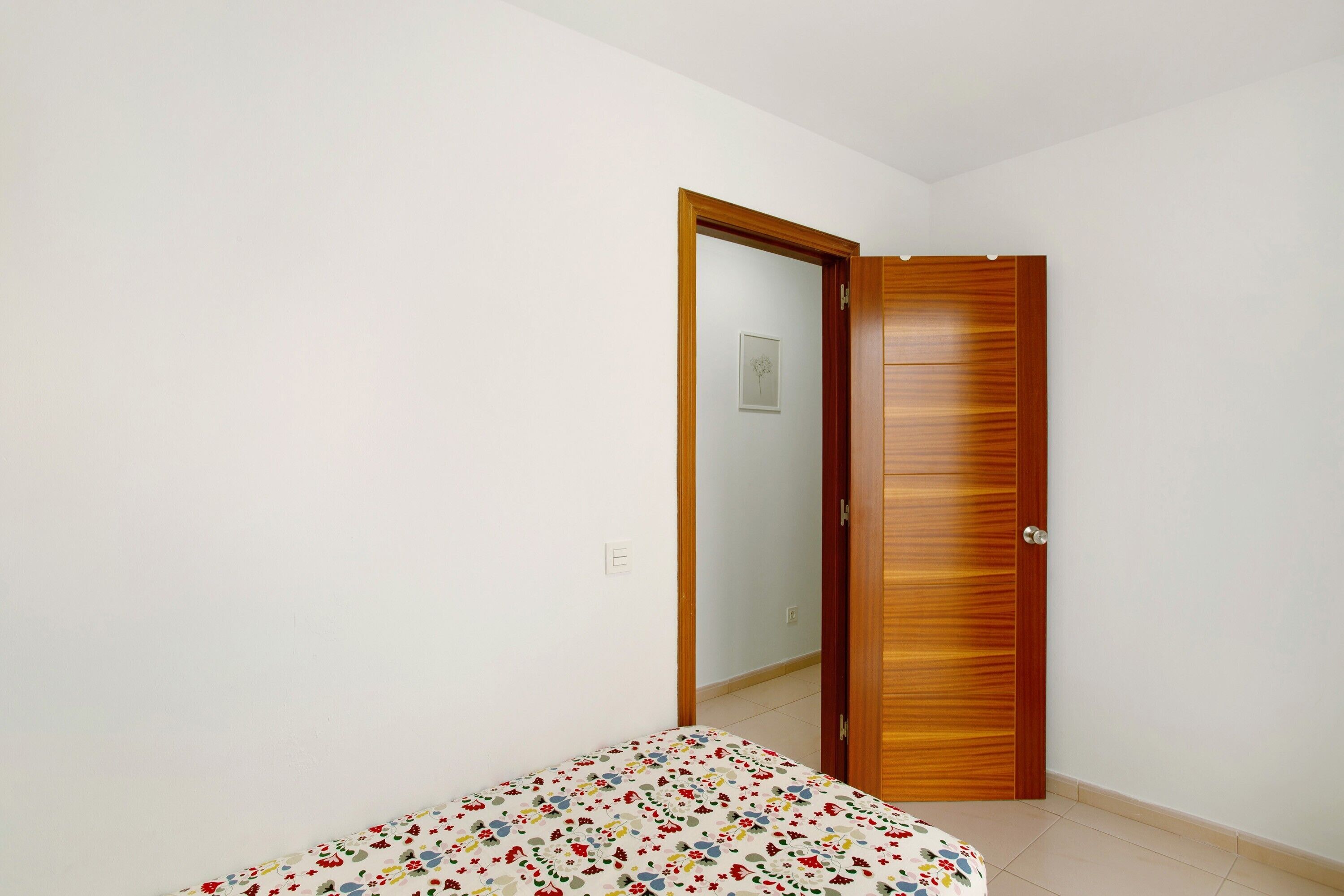 Ein Schlafzimmer mit einem Bett, einer Holztür und einer weißen Wand.