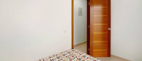 Ein Schlafzimmer mit einem Bett, einer Holztür und einer weißen Wand.