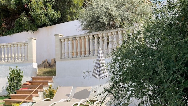 A garden with artificial grass, outdoor seating, a stone staircase, and a decorative fish statue. - Holiday Home "Lola's Beach House" with Sea View, Private Pool & Wi-Fi (Calafell)