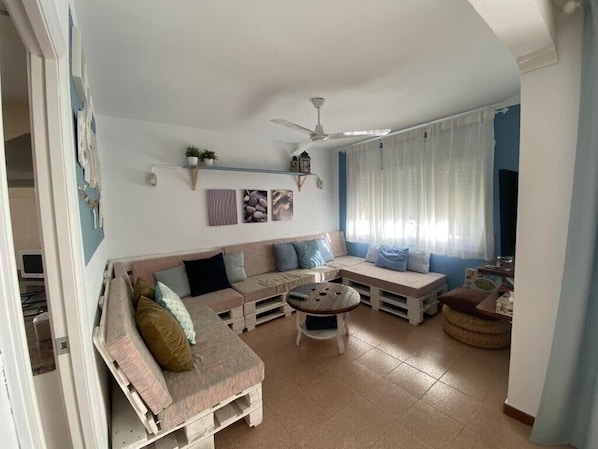 A living room with a sofa, a round coffee table, and a ceiling fan. - Holiday Home "Lola's Beach House" with Sea View, Private Pool & Wi-Fi (Calafell)