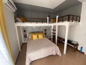 A dorm-style room with bunk beds, a bed, and a small table. - Holiday Home "Lola's Beach House" with Sea View, Private Pool & Wi-Fi (Calafell)