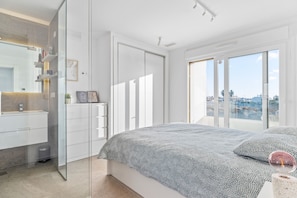 A modern bedroom with a large bed, a glass shower enclosure, and a city view through the windows. - Villa "El Sueño" with Sea View, Private Pool & Wi-Fi (Orihuela)