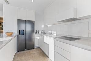 A modern kitchen with white cabinetry, a stainless steel refrigerator, a built-in oven, and a countertop with a sink. - Villa "El Sueño" with Sea View, Private Pool & Wi-Fi (Orihuela)