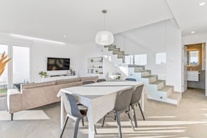 A modern interior with a dining area, sofa, staircase, and kitchen. - Villa "El Sueño" with Sea View, Private Pool & Wi-Fi (Orihuela)