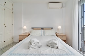 A hotel room with a bed, two bedside lamps, a window, and an air conditioning unit. - Apartment 'Superb  Nerja' with shared pool, Wi-Fi, Air-Con, near Burriana Beach (Nerja)