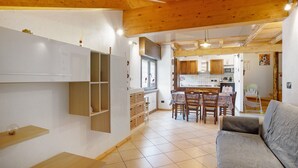 A modern interior with a wooden ceiling, a dining area with chairs, a sofa, and a kitchen with cabinets and appliances. - Apartment "Casa Michod - Nonno Marcel" with Mountain View in Chatillon (Chatillon)