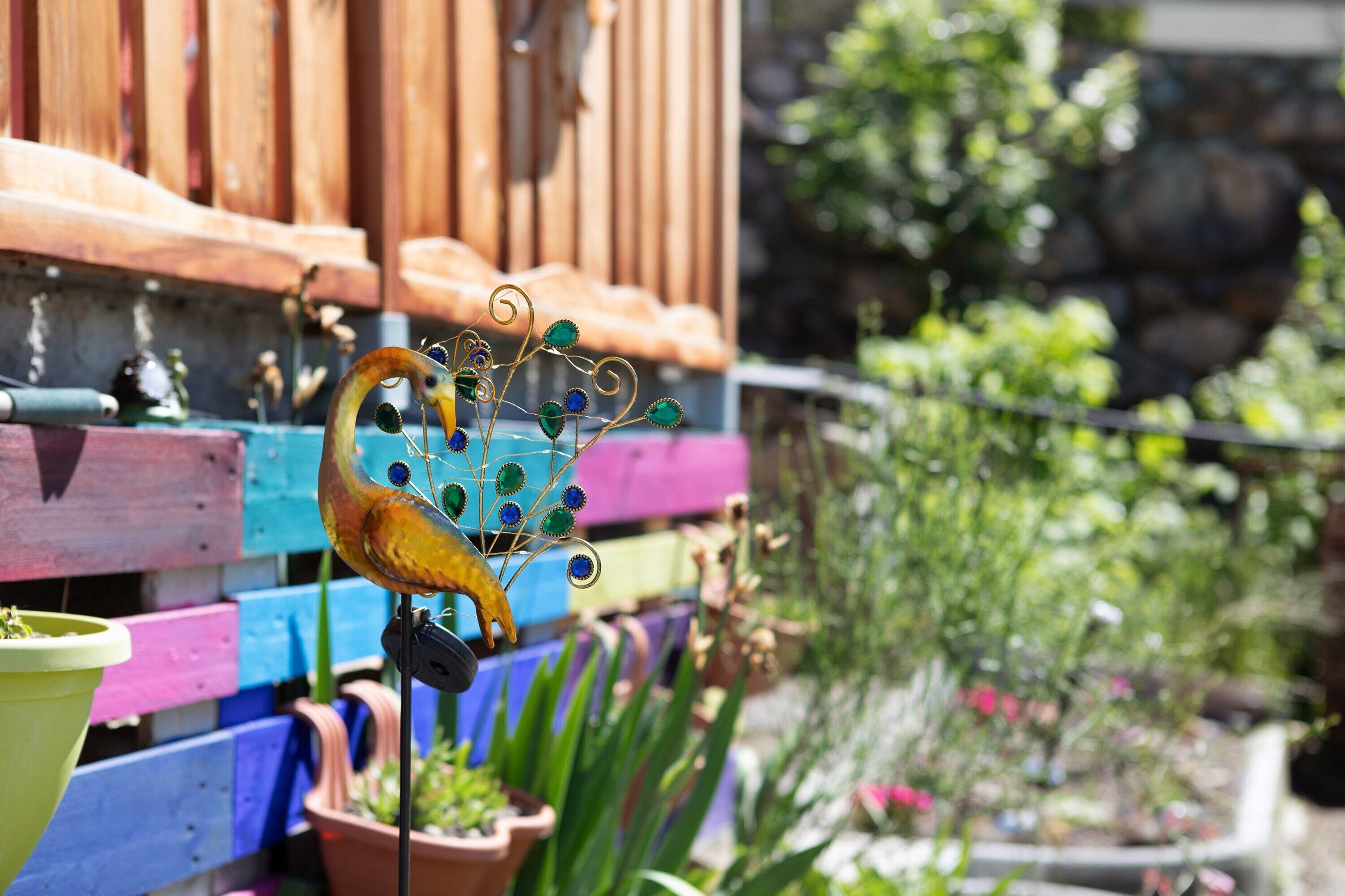 Une clôture en bois aux couleurs vives, avec une sculpture métallique décorative en premier plan.