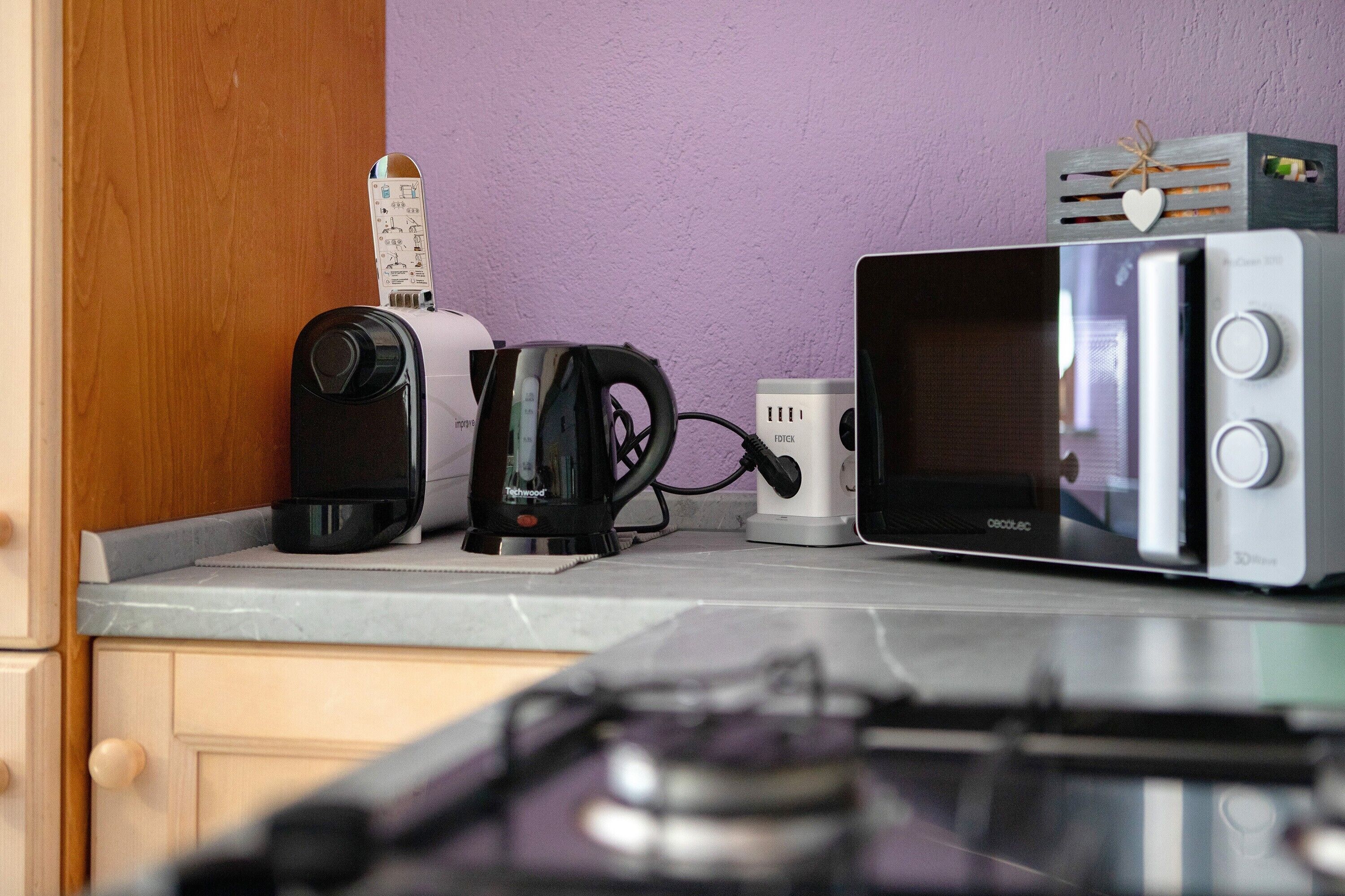 A kitchen with a toaster, kettle, and microwave on the counter.