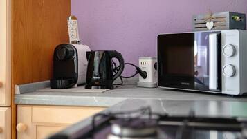 A kitchen with a toaster, kettle, and microwave on the counter.