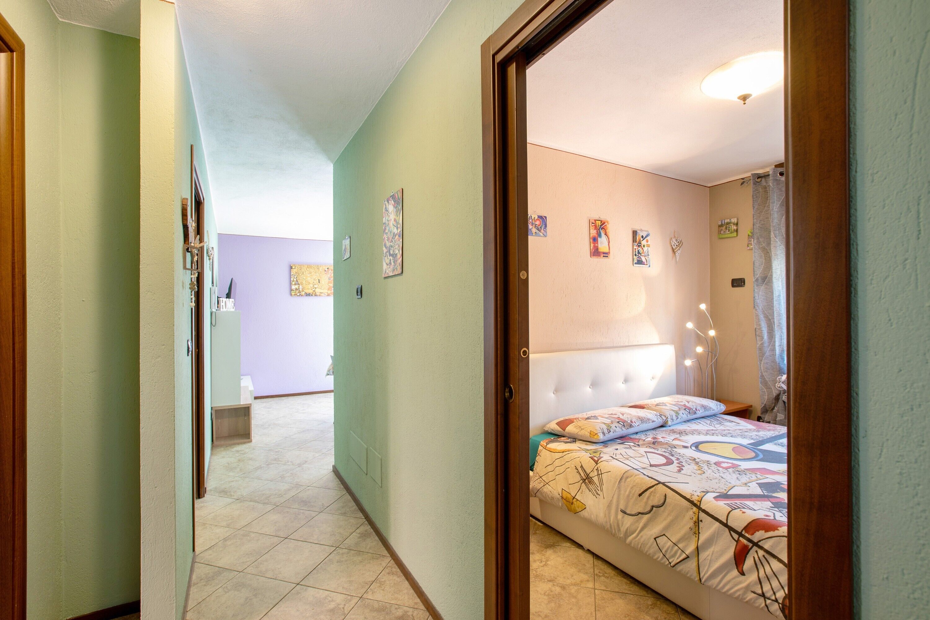 Een slaapkamer met een bed, een hoofdeinde en een muur met foto's.