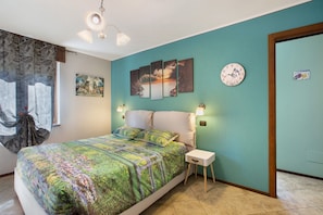 Une chambre à coucher comprenant un lit, une table de chevet, une horloge murale et des œuvres d’art.