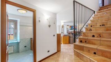 Un escalier avec une rampe, un couloir avec un radiateur et une porte donnant sur une salle de bain.