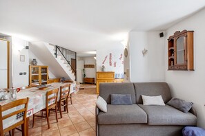 Un salon comprenant un canapé, une table à manger, des chaises et un escalier.