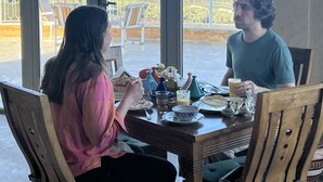 A dining area with a table set for two, large windows offering a view of the landscape, and a balcony with chairs. - Bhalil Farm House  (Bhalil)
