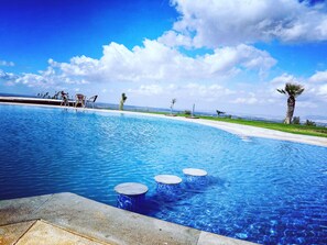 A clear blue pool with three circular steps leading into it, surrounded by a concrete deck. - Bhalil Farm House (Bhalil)