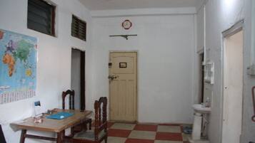 A small room with a wooden table, two chairs, a map on the wall, a clock, and a door.