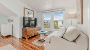 A living room with a TV, wooden dresser, and a view of the outdoors. - THE BLUE HOUSE AT OLD COLORADO INN (Stuart)