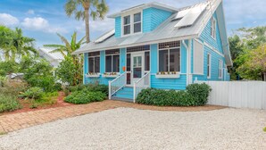 A two-story house with a blue exterior, a front porch with a white railing, and a gravel driveway. - THE BLUE HOUSE AT OLD COLORADO INN (Stuart)
