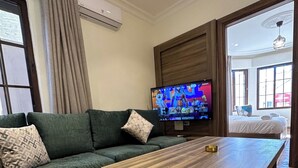A modern living room with a sectional sofa, a wooden coffee table, a flat-screen TV, and a large window. - 1 Antika Jabalal-lovebdeh (Amman)