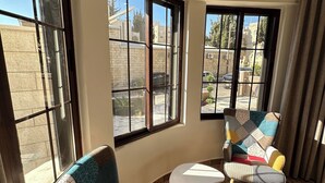 A room with two armchairs, a small white table, and large windows with a view of buildings and trees. - 1 Antika Jabalal-lovebdeh (Amman)