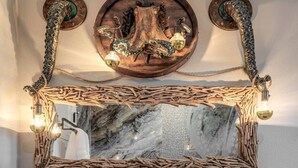 A bathroom with a large mirror, two stone sinks, wooden cabinets, and a decorative wooden frame above the mirror.