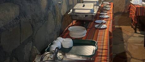 A buffet setup with multiple serving stations, a stone wall, and a tiled floor.