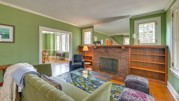 A living room with a green wall, a fireplace, a sofa, a coffee table, and a bookshelf. - Near Downtown Cincinnati: Peaceful Retreat! (Cincinnati)