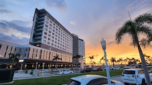 Un hôtel au design moderne, avec une enseigne « LUMINARY » bien visible, un parking et des palmiers.
