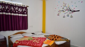 A bedroom with a wooden bed, purple curtains, a yellow accent wall, and a wall decoration of a tree with hanging birdcages. - binay chapa homestay Jaldapara wildlife sanctuary best leving accommodation  (Madhya Madarihat)