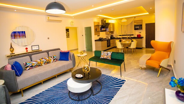 A modern living room with a sofa, coffee table, and a dining area with chairs and a table.