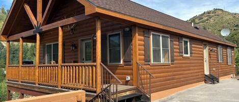 A log cabin with a porch, a staircase, and a satellite dish.