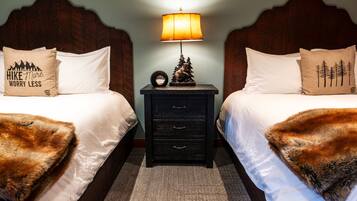 A hotel room with two beds, each with a wooden headboard, a nightstand with a lamp, and decorative pillows.
