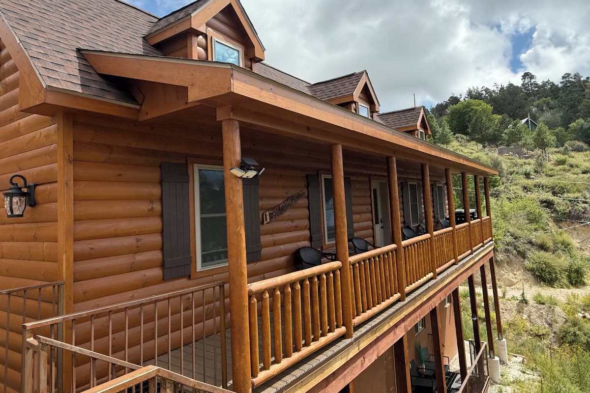 Een vakantiehuis van hout met een houten terras en meerdere ramen.