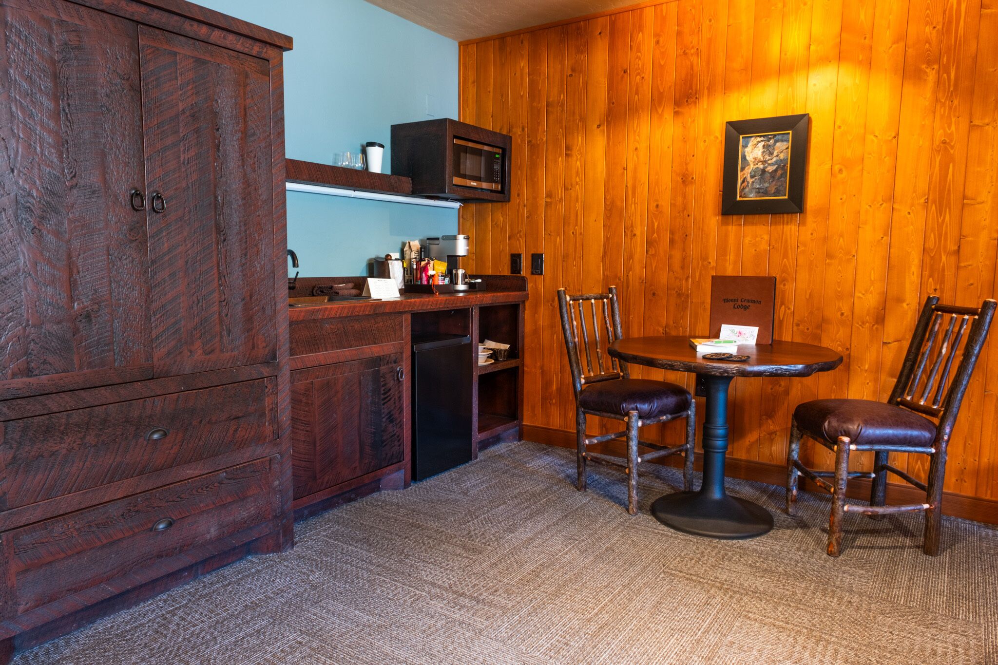 A wooden-paneled room with a dining table and chairs, a microwave, and a cabinet.