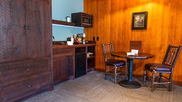 A wooden-paneled room with a dining table and chairs, a microwave, and a cabinet.