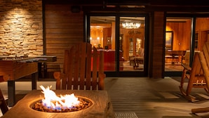 A cozy indoor setting with a wooden table, a fire pit, and a rocking chair. - Mount Lemmon Lodge (Mount Lemmon)