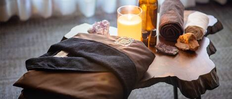 A spa setting with a towel, candle, and essential oils on a wooden table.