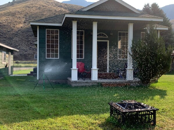 A house with a porch, a lawn, and a mountain in the background.